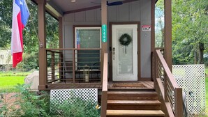 A wooden porch with a glass door, a wreath, and a Texas flag.