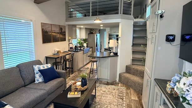 A modern living space with a sofa, coffee table, and a kitchen area.