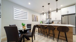 Una cocina moderna con armarios blancos, una isla central con taburetes de bar e iluminación colgante.
