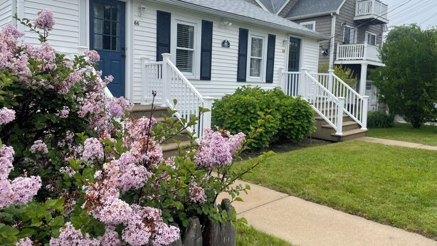 A two-story house with a front porch, a mailbox, and a well-maintained lawn.