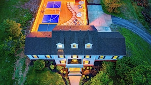 A large house with a tennis court, a swimming pool, and a well-maintained garden.