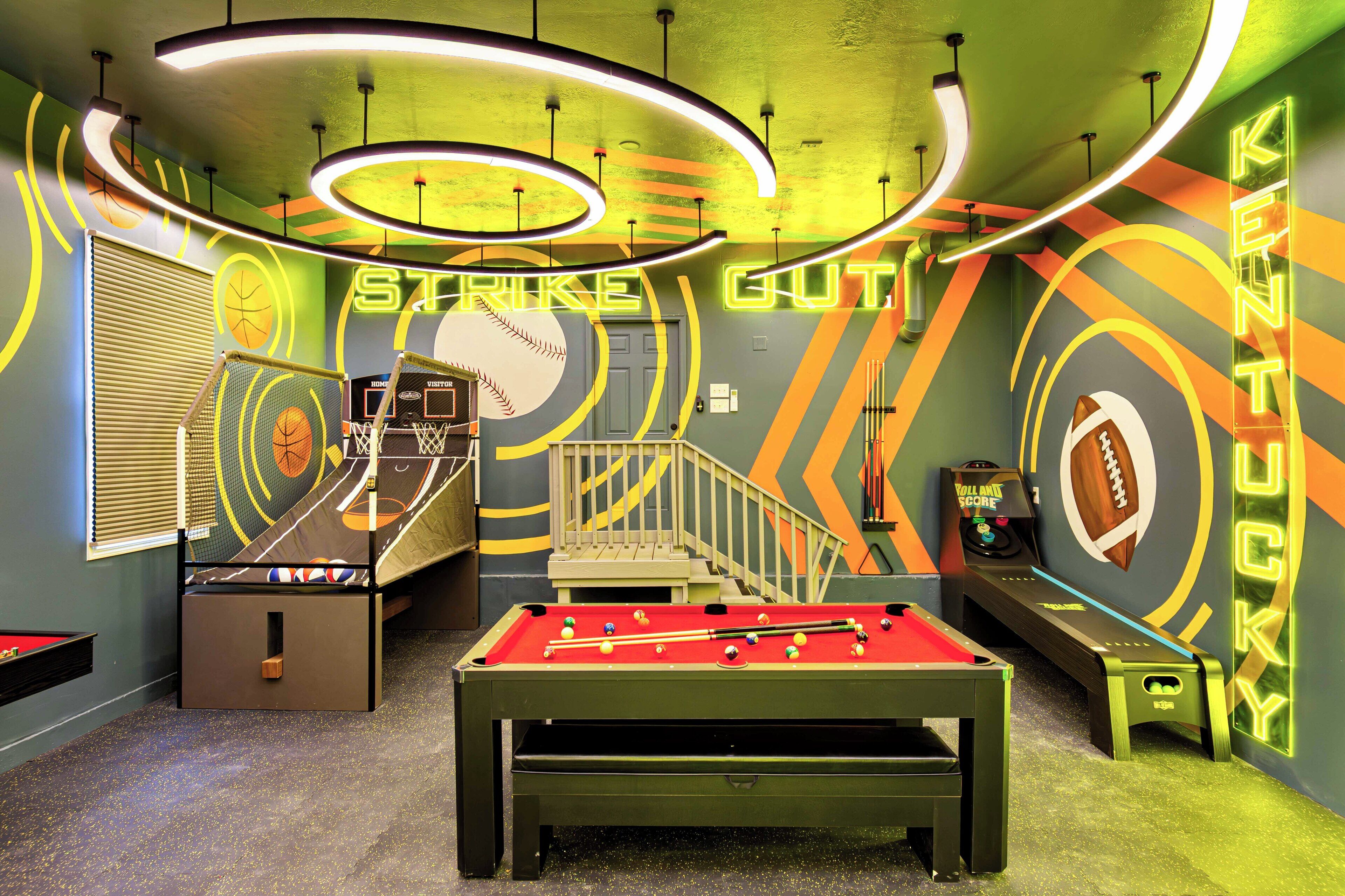 A room with a pool table, foosball table, and a dartboard.