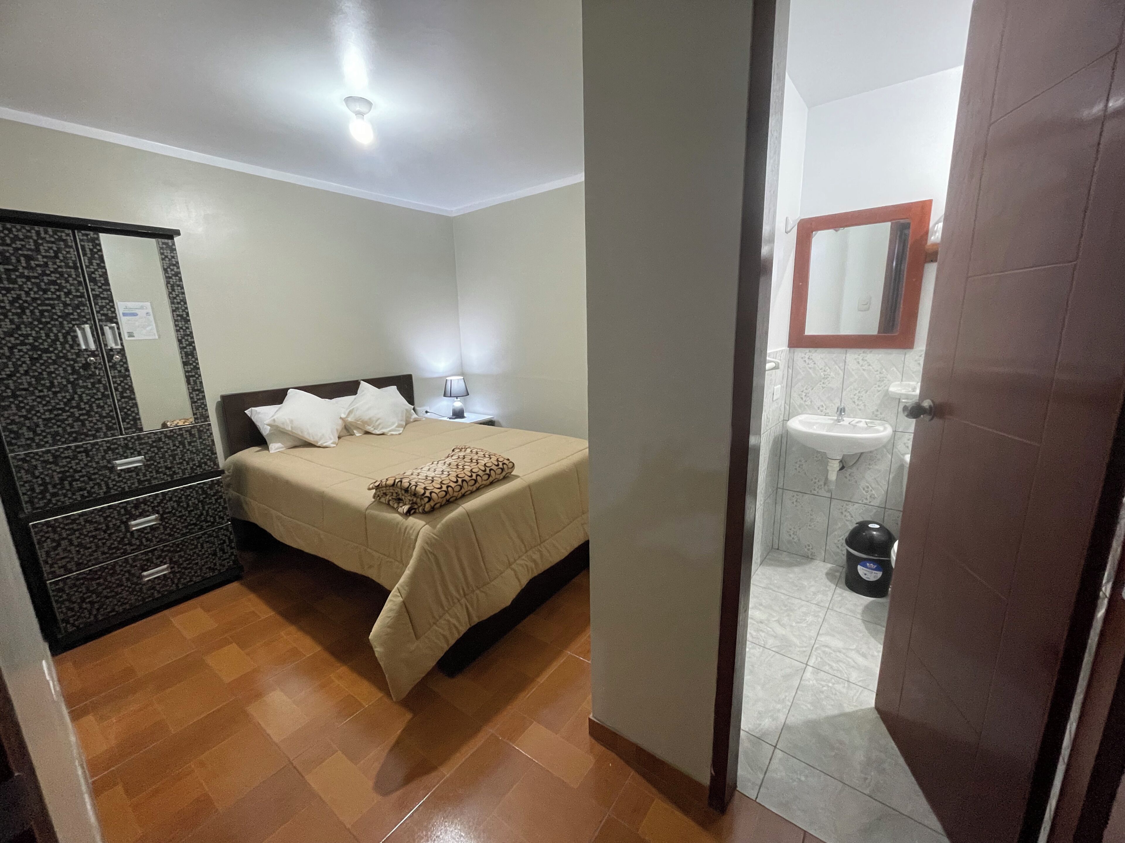 Une chambre à coucher comprenant un lit, une table de chevet, une lampe et une armoire.