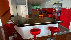 Une cuisine moderne avec un îlot central, des tabourets de bar rouges et un réfrigérateur.