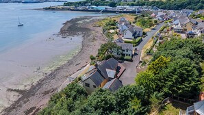 A coastal residential area with houses, a beach, and a distant industrial area. - Rhyd y Groes Bach, Holiday Cottage Burton, Sleeps 6, 3 bedrooms,  bathrooms (Milford Haven)