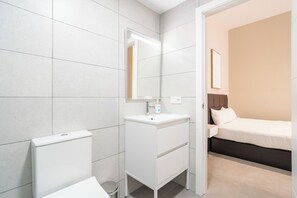 A modern bathroom with a white sink, mirror, and toilet. - VLC HOST - Sumsi B (Valencia)