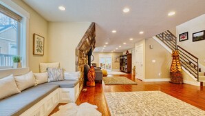 A spacious living room with a wooden floor, a built-in bench, and a staircase with a decorative railing. - MountainTop Mega A Frame Chalet with Hot Tub (Black Hawk)