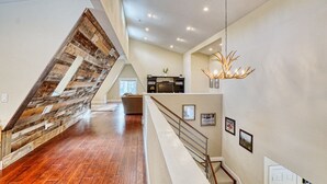 A spacious interior with a wooden staircase, a chandelier, and a kitchen area. - MountainTop Mega A Frame Chalet with Hot Tub (Black Hawk)