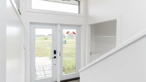 A white interior with a double door leading outside, a staircase, and a view of a grassy area. - New waterfront- 5 bedroom home (Gimli)