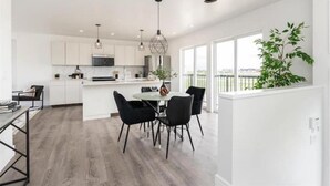 A modern kitchen with white cabinets, a central island, and pendant lighting. - New waterfront- 5 bedroom home (Gimli)