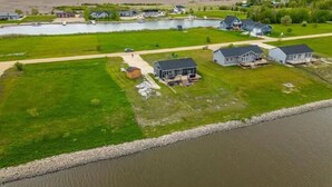 An aerial view of a residential area with houses, a lake, and a river. - New waterfront- 5 bedroom home (Gimli)