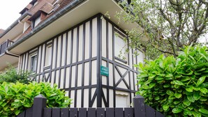 A traditional building with a black and white facade, a gated entrance, and lush green foliage. - Le Surcouf by Interhome (Cabourg)