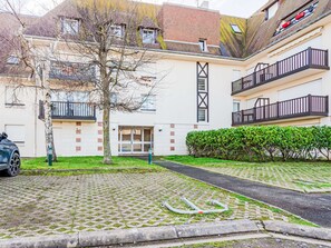 Ein Innenhof mit gepflastertem Bereich, einem Baum und einem Gebäude mit Balkonen und einer Garagentür.