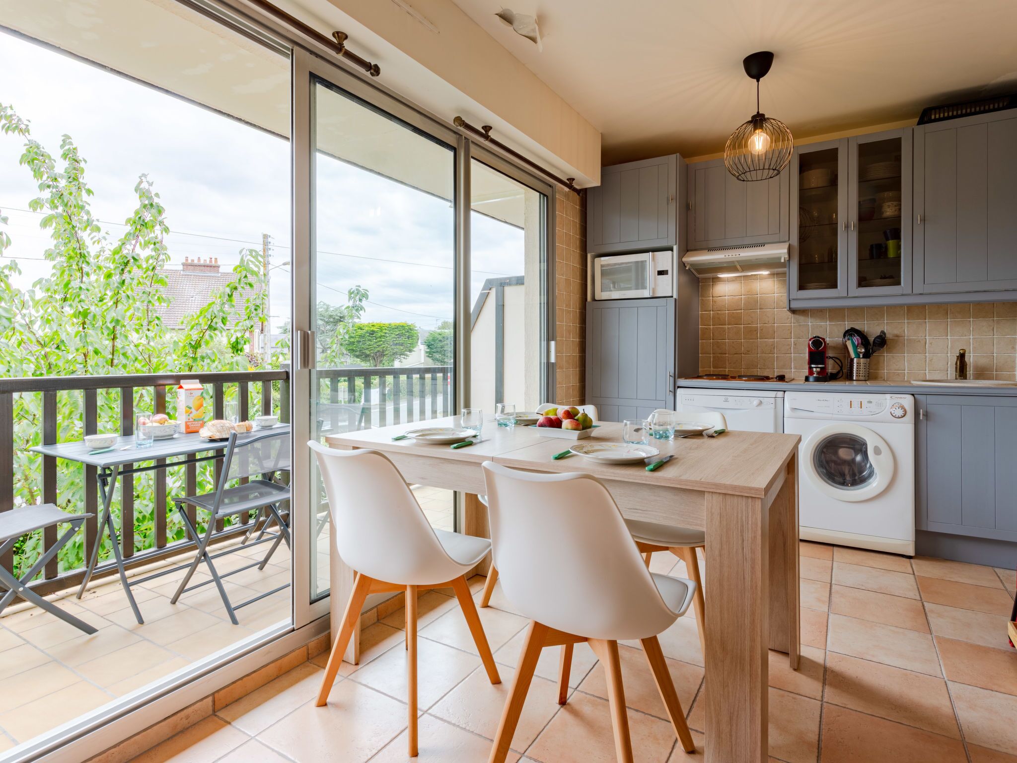 A modern kitchen with a dining area, large windows, and a washing machine.