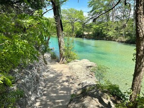 A clear, turquoise river with a stone path leading into the water, surrounded by dense greenery. - Adorable cabin STEPS away From the Crystal Clear Frio River - Terrace #3 (Concan)