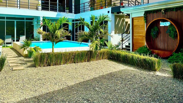 A modern two-story house with a swimming pool, a wooden deck, and a circular wooden structure.
