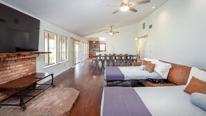 A spacious room with a brick fireplace, a large bed, a dining area, and a kitchen. - Serene Riverfront Home · Hot Tub + Private River Access – Just 150 Yards Away (Three Rivers)