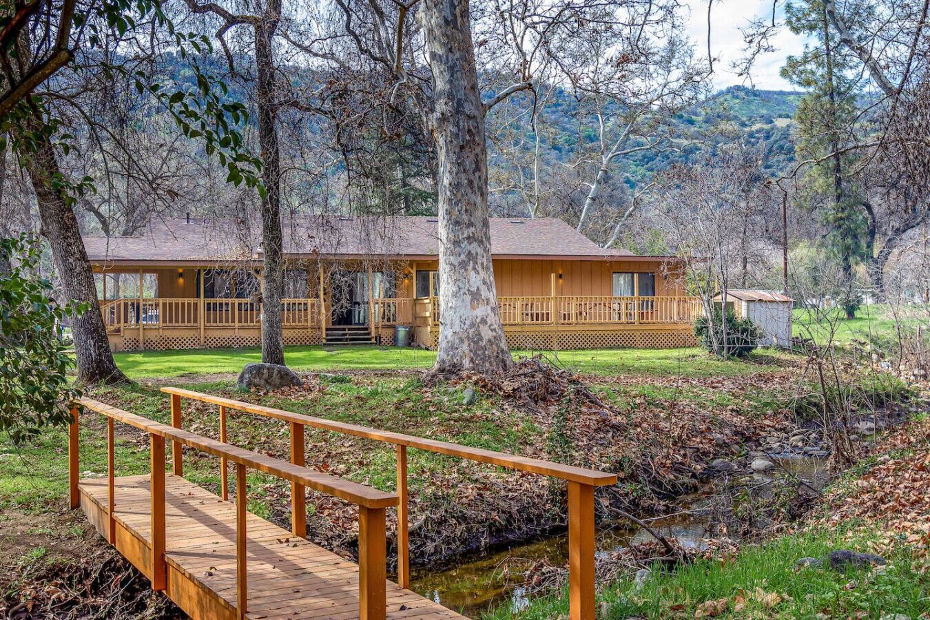 A lodge with a wooden deck, a porch, and a small shed.