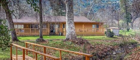 A lodge with a wooden deck, a porch, and a small shed.