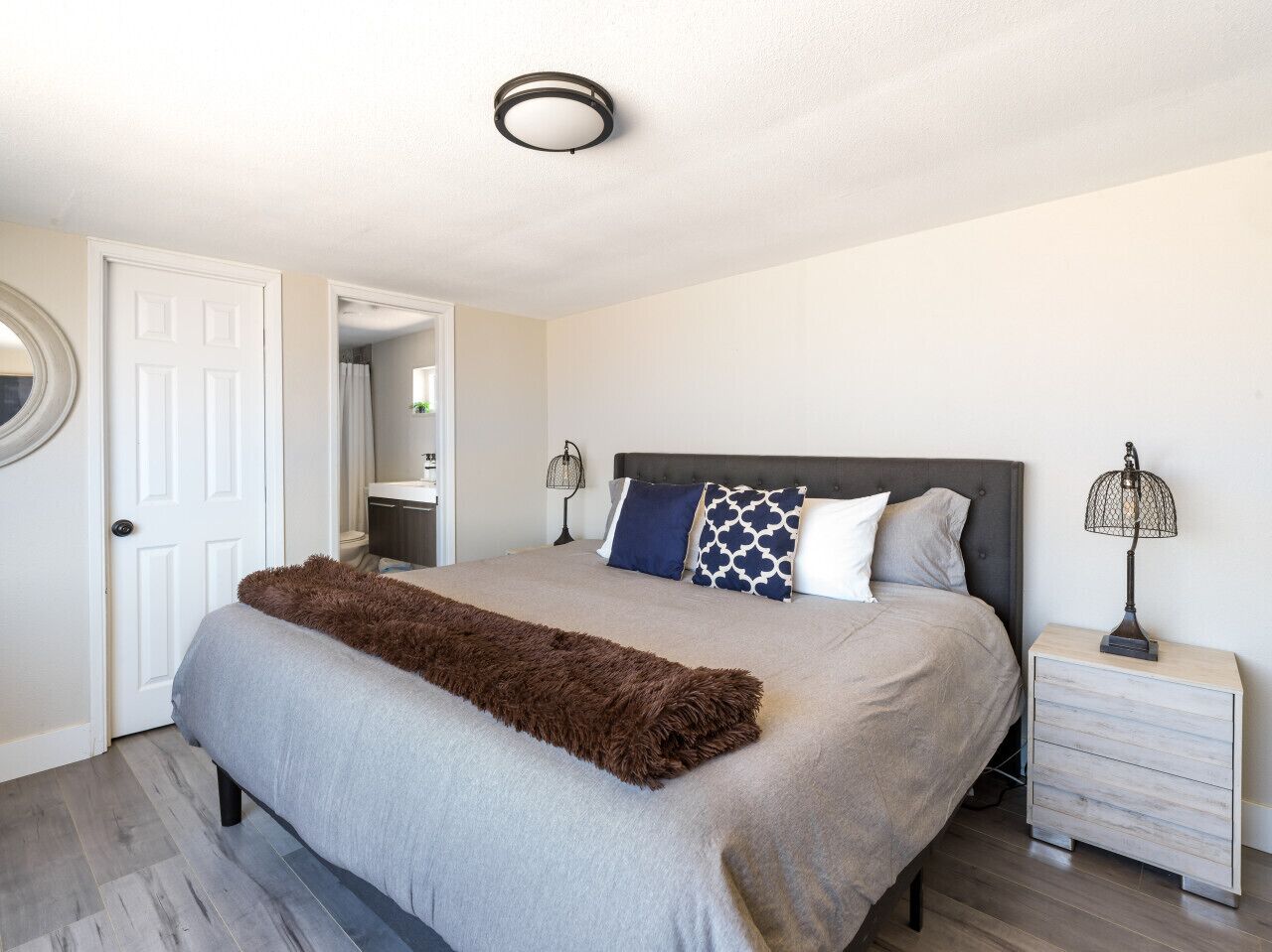 A bedroom with a bed, bedside tables, a door, and a ceiling light.