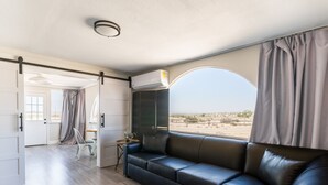Um interior moderno com sofá seccional, uma mesinha e vista para o deserto.