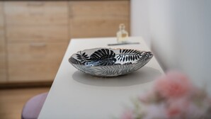 Un cuenco con diseño de hojas sobre una mesa en una habitación con armarios de madera.