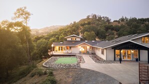 Una casa a due piani con un patio, una piscina e vista su un paesaggio collinare.
