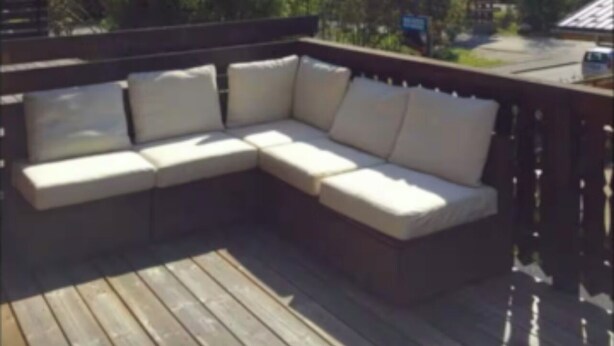 Una terraza de madera con un sofá modular que da a un paisaje montañoso.