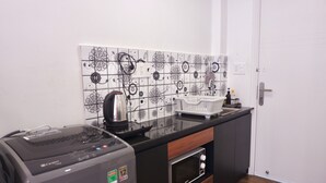 A compact kitchen with a coffee maker, a microwave, and a dishwasher. - Cozy Studio Apartment (Ho Chi Minh City)