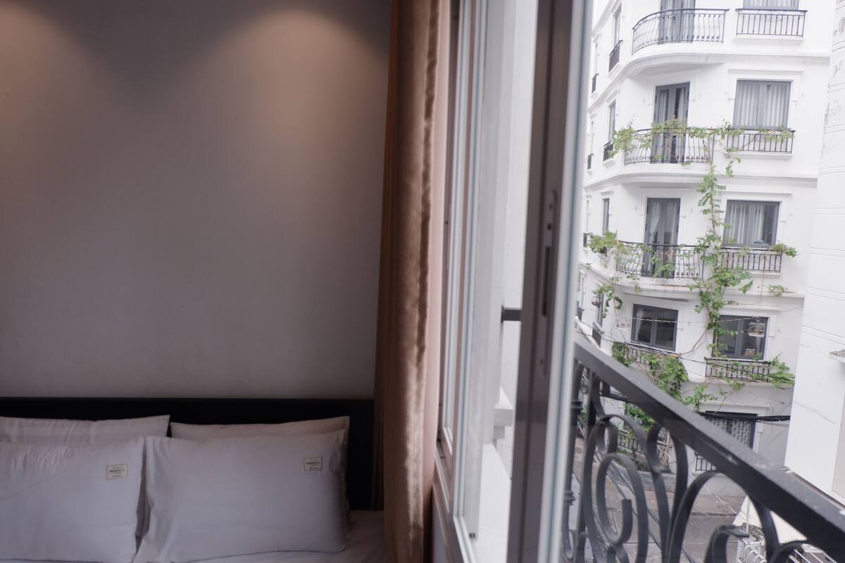 Ein Hotelzimmer mit Bett und Fenster mit Blick auf ein Gebäude mit Balkonen.