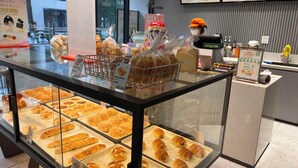 Mostrador de panadería con distintos productos horneados, una caja registradora y un panel de menú.