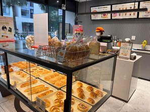Mostrador de panadería con distintos productos horneados, una caja registradora y un panel de menú.