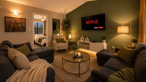 A modern living room with a sofa set, a coffee table, a TV mounted on the wall, and a side table with a lamp. - Austin 3BR Home for Families & Groups · Sleeps 10 · 10min to UT (Austin)