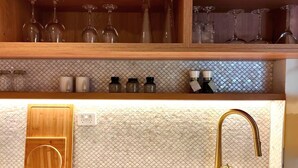 A kitchen with a wooden countertop, a gold faucet, and a tiled backsplash. - Tui Studio | New Reno| Self Contained | Near City (Auckland)