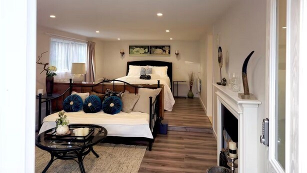 A bedroom with a bed, bedside table, lamp, and a fireplace. - Tui Studio | New Reno| Self Contained | Near City (Auckland)
