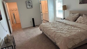 A bedroom with a large bed, a desk, a chair, a lamp, and a picture on the wall. - Spacious 5-bedroom house in welcoming Sebastian with WiFi, AC (Vero Beach)