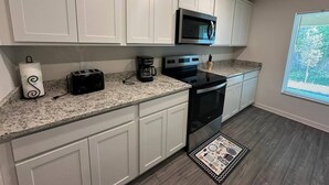 A kitchen with white cabinets, a microwave, a toaster, a coffee maker, and a stove. - Spacious 5-bedroom house in welcoming Sebastian with WiFi, AC (Vero Beach)