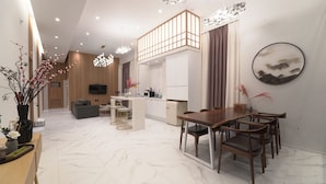 A modern living room with a sofa, dining table, and chairs, a kitchen area with a microwave, and a TV mounted on the wall. - BUSAN ALMOND KIDS POOL VILLA NAMPO (Busan)
