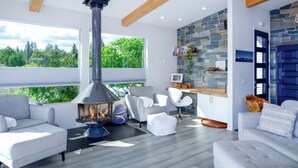 Un salon moderne avec un mur en pierre, une cheminée et une vue sur la verdure.