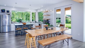 Une cuisine moderne dotée d’un grand îlot central, de tabourets en bois et d’une table à manger avec des bancs.