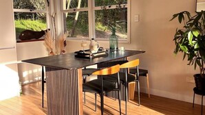 Een moderne keuken met een groot schiereiland, houten vloeren en grote ramen met uitzicht op de omgeving.
