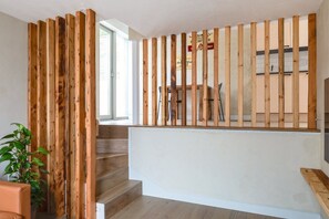 Una escalera de madera con una pared blanca y una planta a la izquierda.