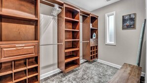 Un dressing accessible sans porte, doté d’étagères et de tiroirs ouverts, d’un miroir et d’un tableau encadré au mur.