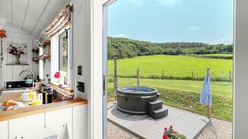 A kitchen with a view of a hot tub and a grassy field.