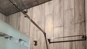 A shower area with wooden paneling, a glass door, and a metal towel rack.