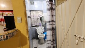 Ein Badezimmer mit Toilette, einer Duschvorhang und einer gefliesten Wand.