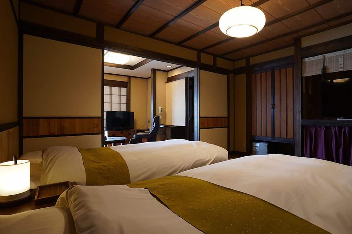 Habitación de hotel con dos camas, televisión, escritorio y ventana con cortinas.