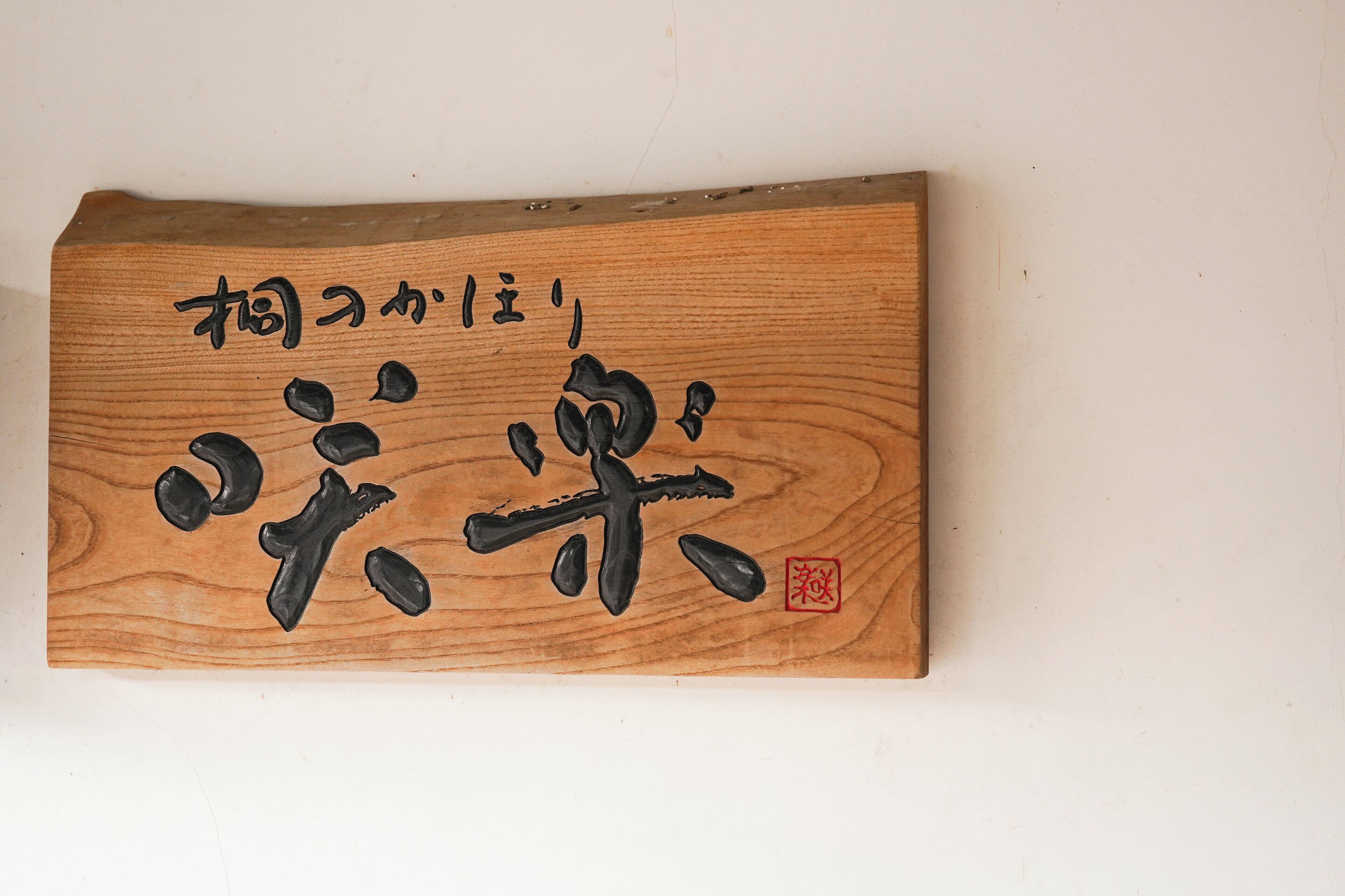 A wooden plaque with Japanese calligraphy and a red seal.