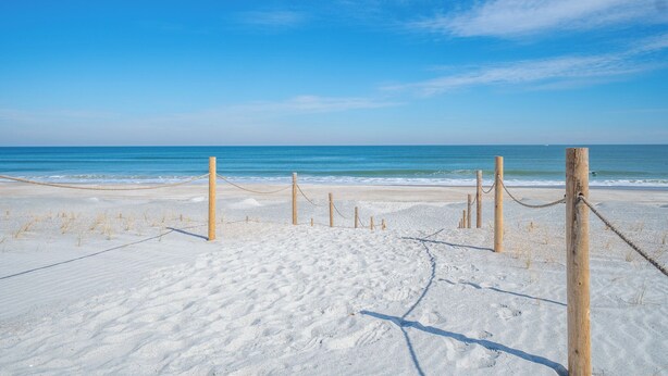A sandy beach with wooden posts and ropes forming a barrier.