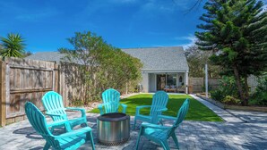 A patio with four turquoise Adirondack chairs and a metal fire pit.